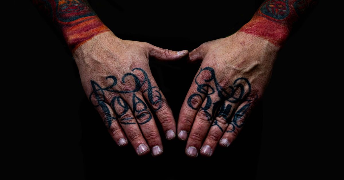 Close view of a tattooed forearm resting on a studio table under soft light